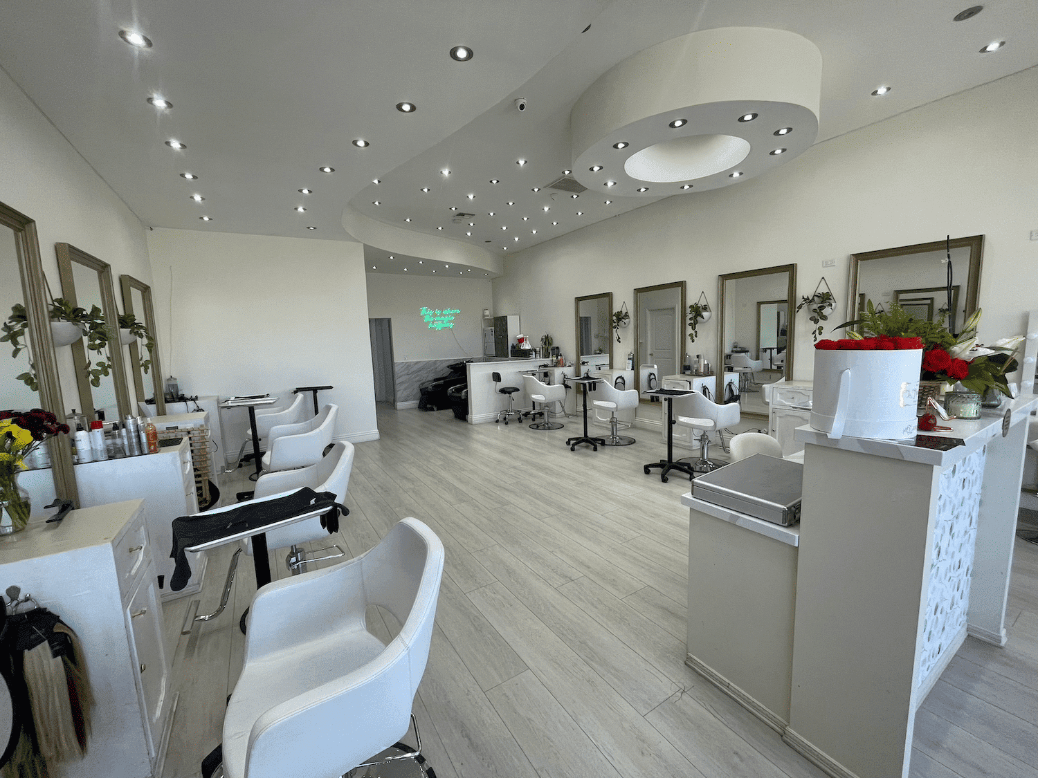 Modern salon interior with white chairs, mirrors, and stylish lighting.