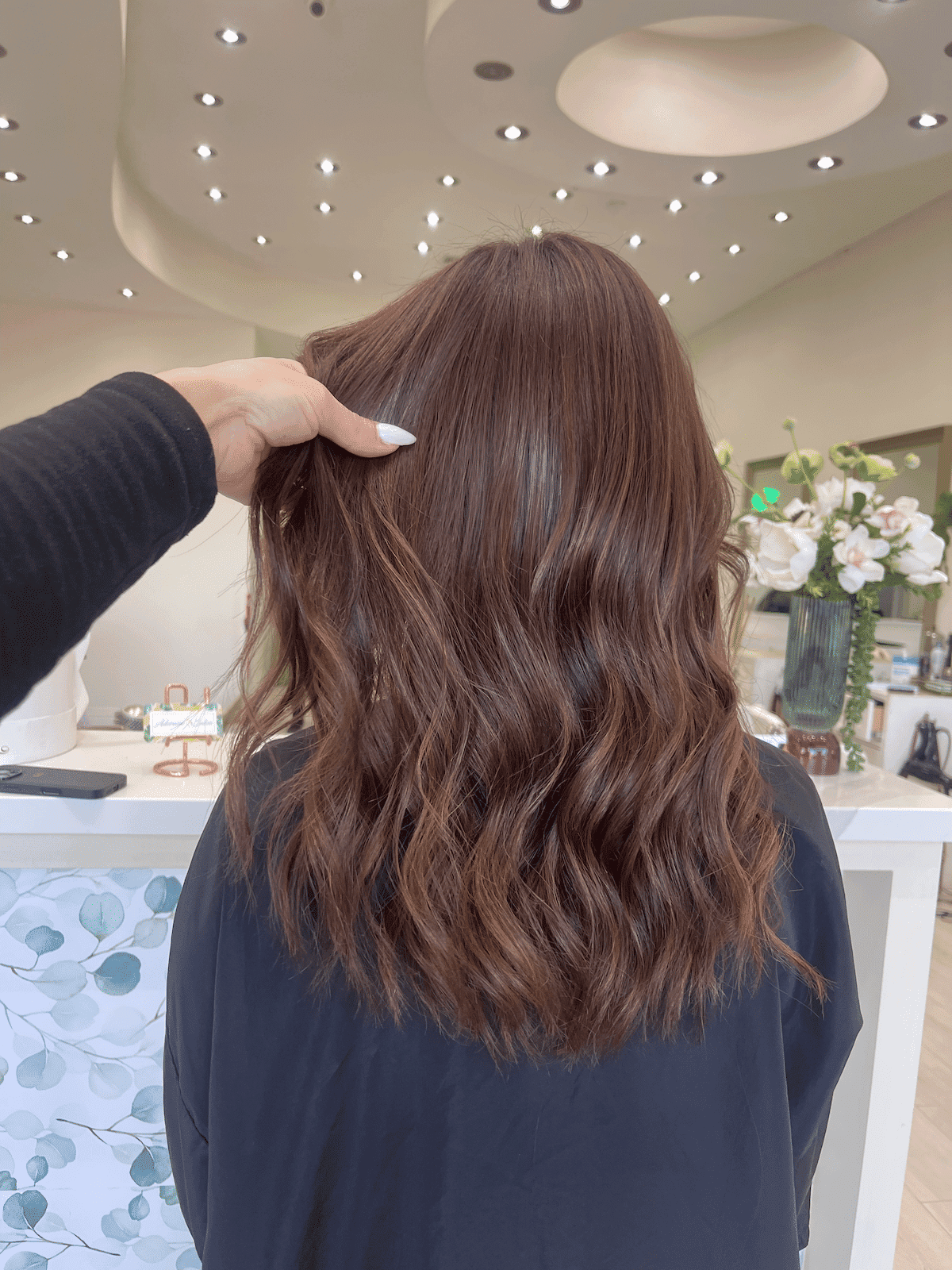 Wavy, brown hair styled in salon under modern ceiling lights.